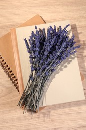 Bouquet of beautiful preserved lavender flowers and notebooks on wooden table, top view