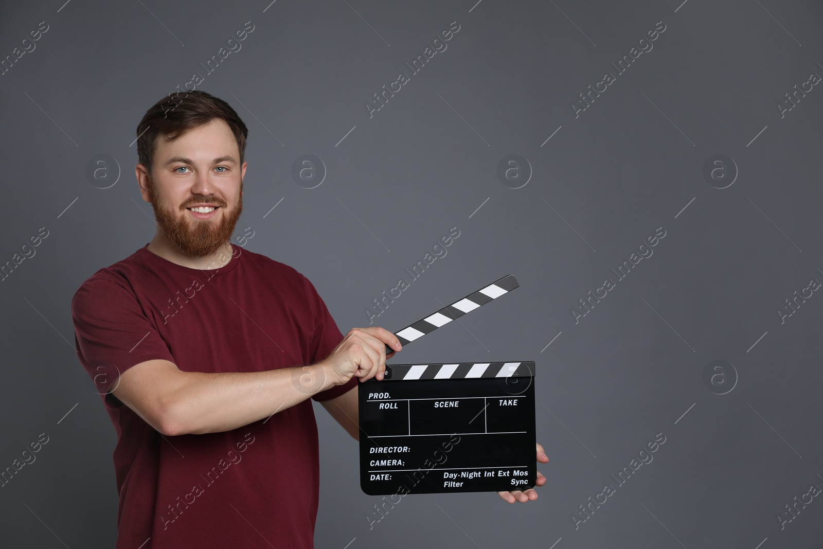 Photo of Making movie. Smiling man with clapperboard on grey background. Space for text