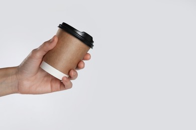 Woman holding takeaway paper coffee cup on white background, closeup. Space for text