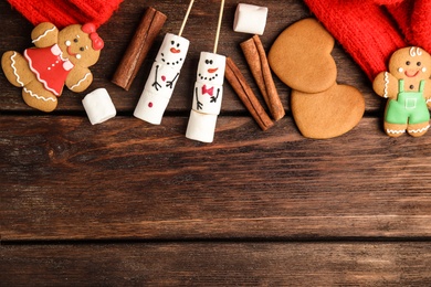 Flat lay composition with funny snowmen made of marshmallows on wooden table, space for text