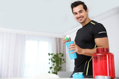 Photo of Young athletic man preparing protein shake at home, space for text