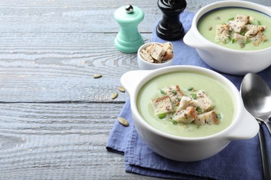 Photo of Delicious asparagus soup with croutons served on grey wooden table, space for text