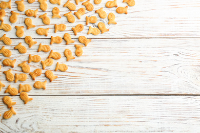 Delicious goldfish crackers on white wooden table, flat lay. Space for text