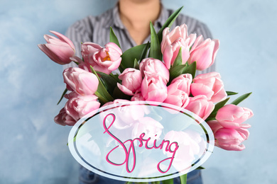 Image of Woman with beautiful pink tulips on light blue background, closeup. Hello spring