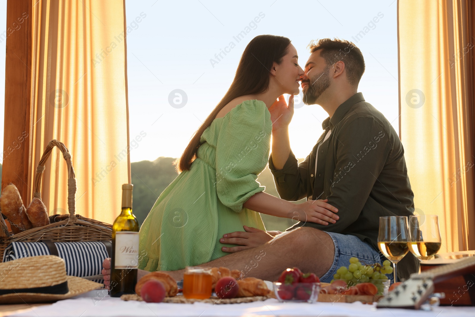 Photo of Romantic date. Beautiful couple kissing during picnic on sunny day