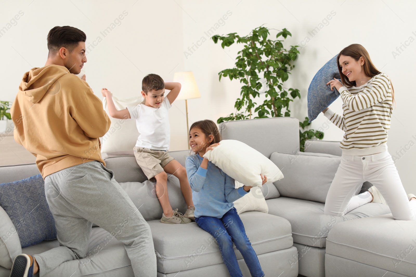 Photo of Happy family having pillow fight in living room