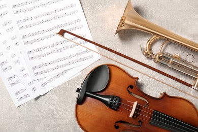 Photo of Violin, trumpet and note sheets on light grey background, flat lay. Musical instruments