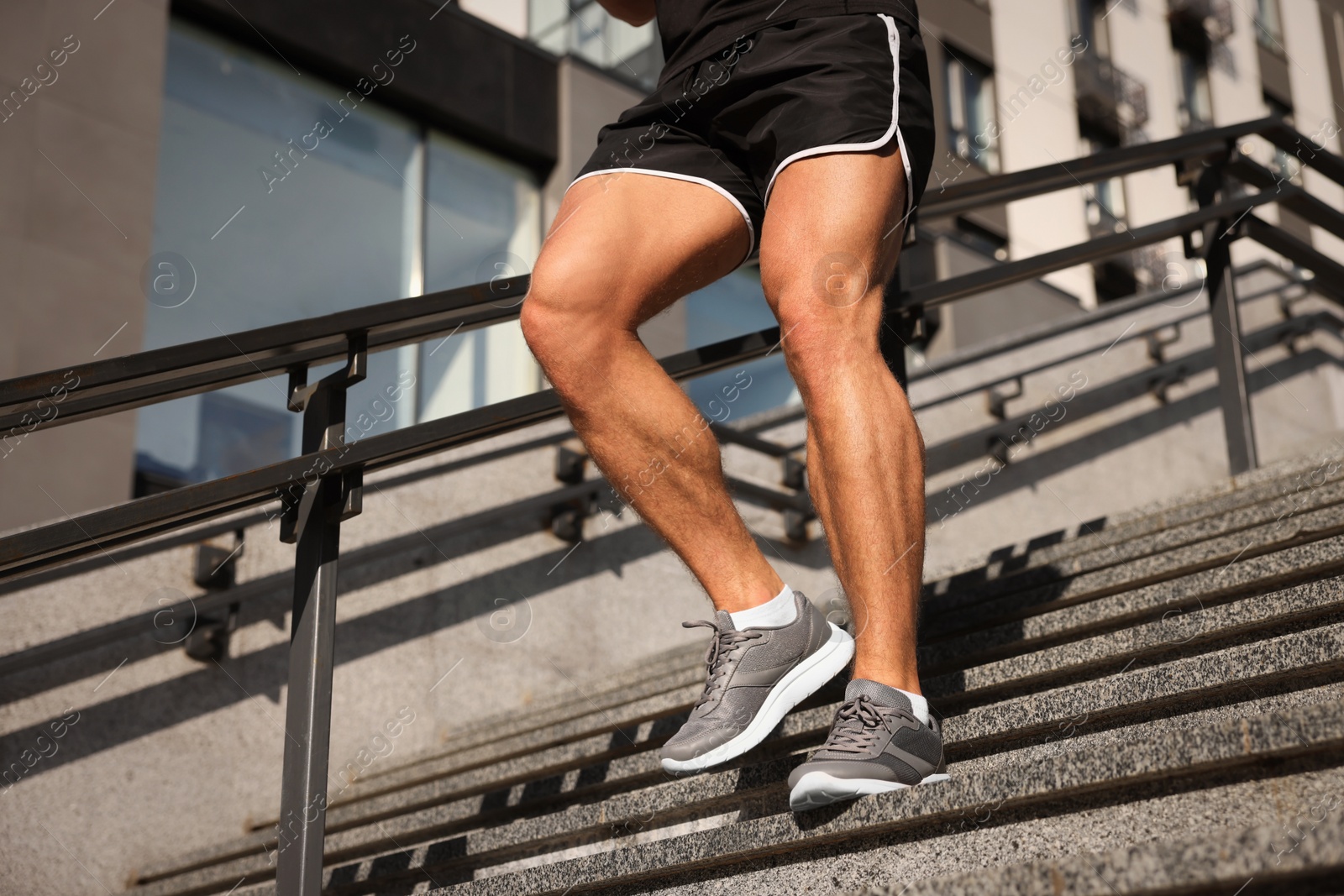 Photo of Man running down stairs outdoors on sunny day, closeup