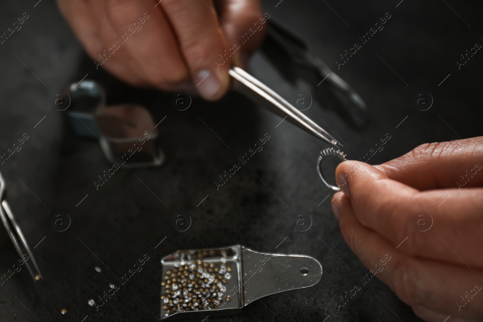 Photo of Male jeweler examining diamond ring in workshop, closeup view