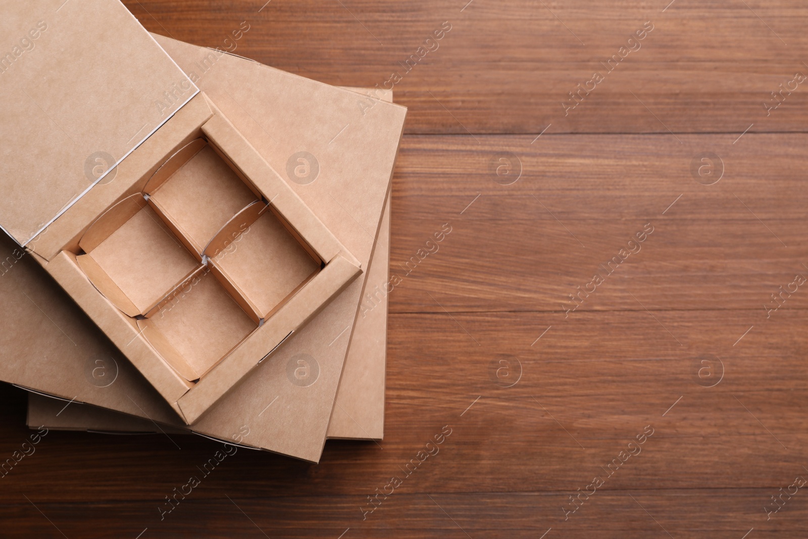 Photo of Stack of candy boxes on wooden background, top view. Space for text