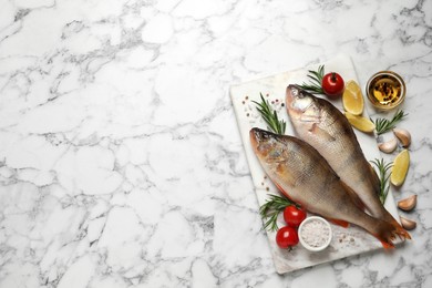 Fresh raw perches and ingredients on white marble table, flat lay with space for text. River fish