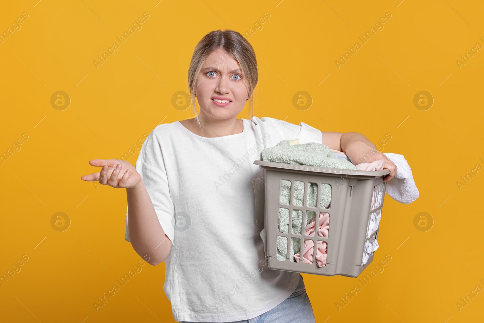 Photo of Young woman with basket full of laundry on orange background