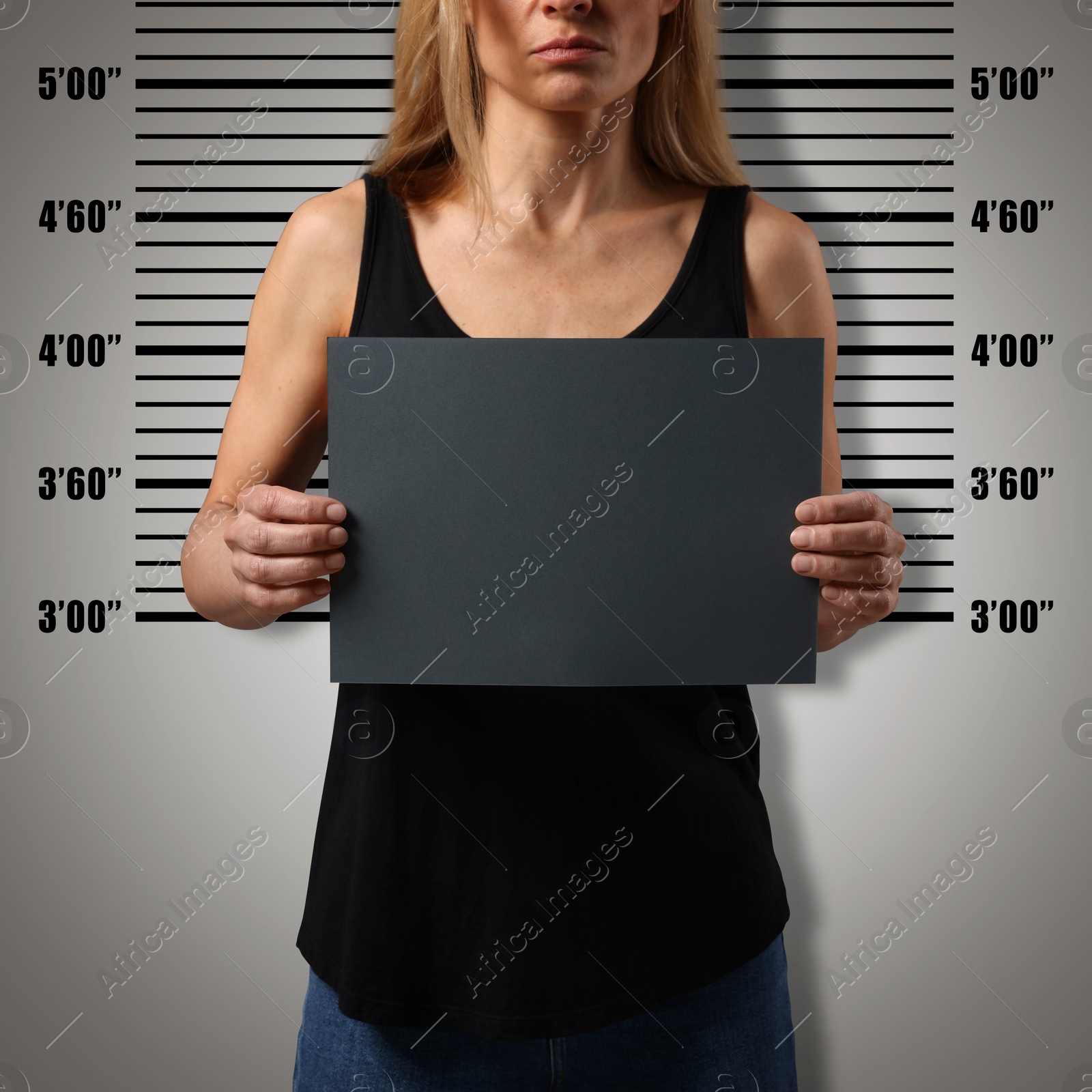 Image of Criminal mugshot. Arrested woman with blank card against height chart, closeup