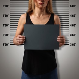 Image of Criminal mugshot. Arrested woman with blank card against height chart, closeup
