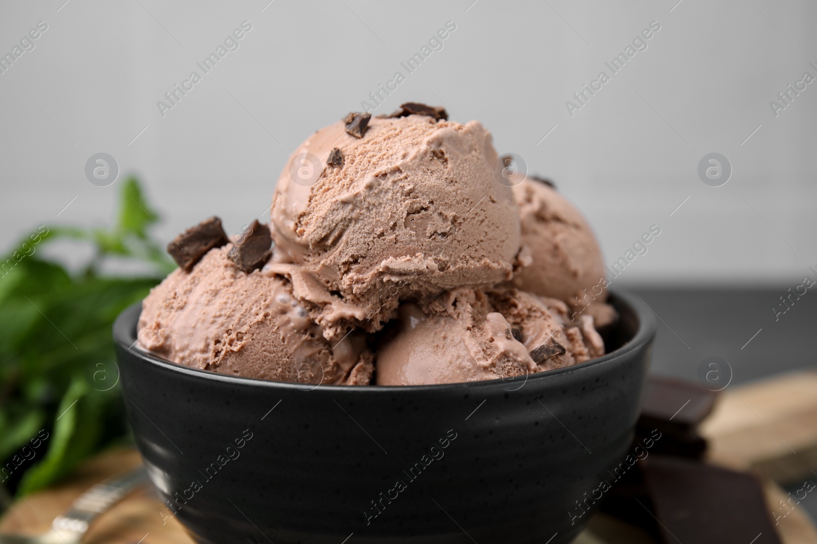 Photo of Bowl with tasty chocolate ice cream on blurred background, closeup