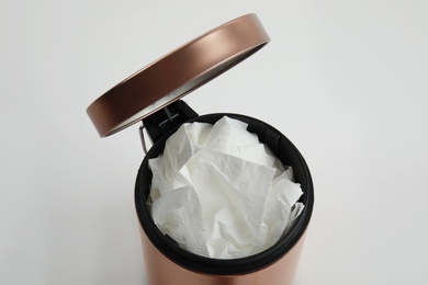 Trash bin with used toilet paper on white background