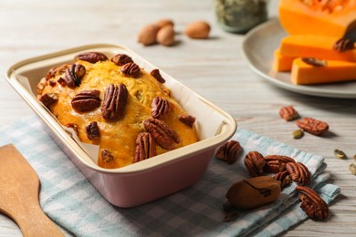 Photo of Delicious pumpkin bread with pecan nuts on light wooden table
