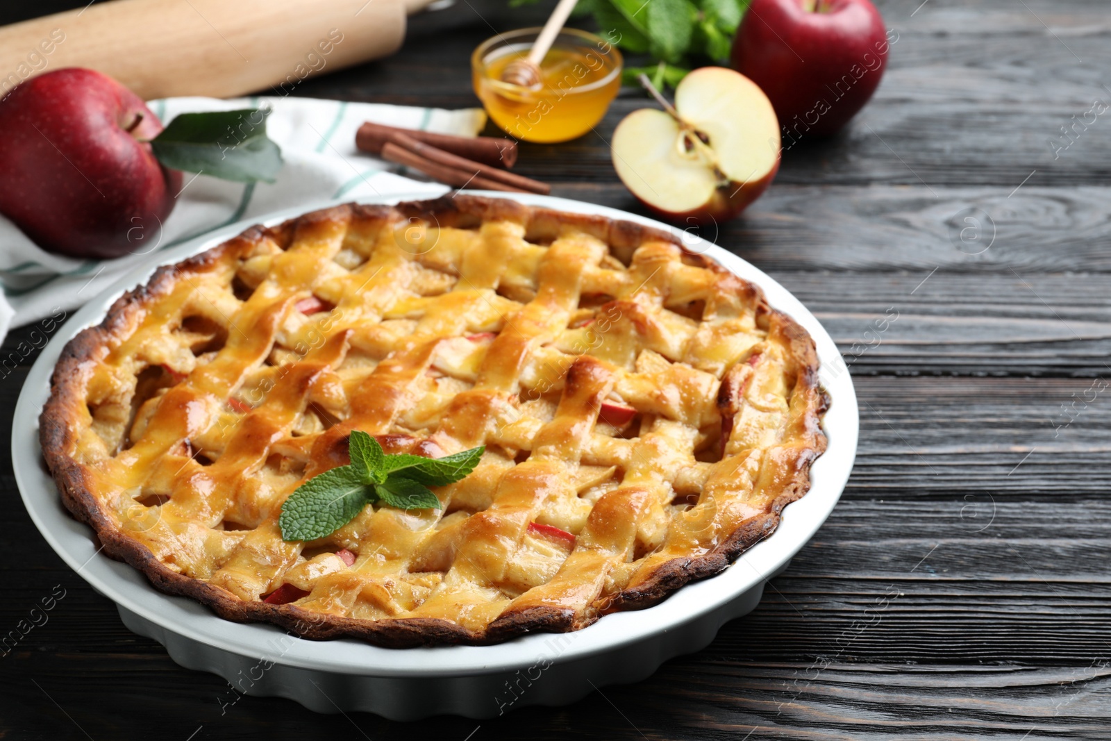 Photo of Traditional apple pie with mint on black wooden table