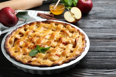 Photo of Traditional apple pie with mint on black wooden table