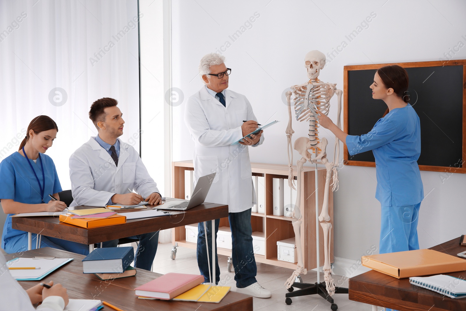 Photo of Medical students and professor studying human skeleton anatomy in classroom