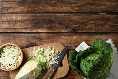 Whole and cut fresh savoy cabbages on wooden table, flat lay. Space for text