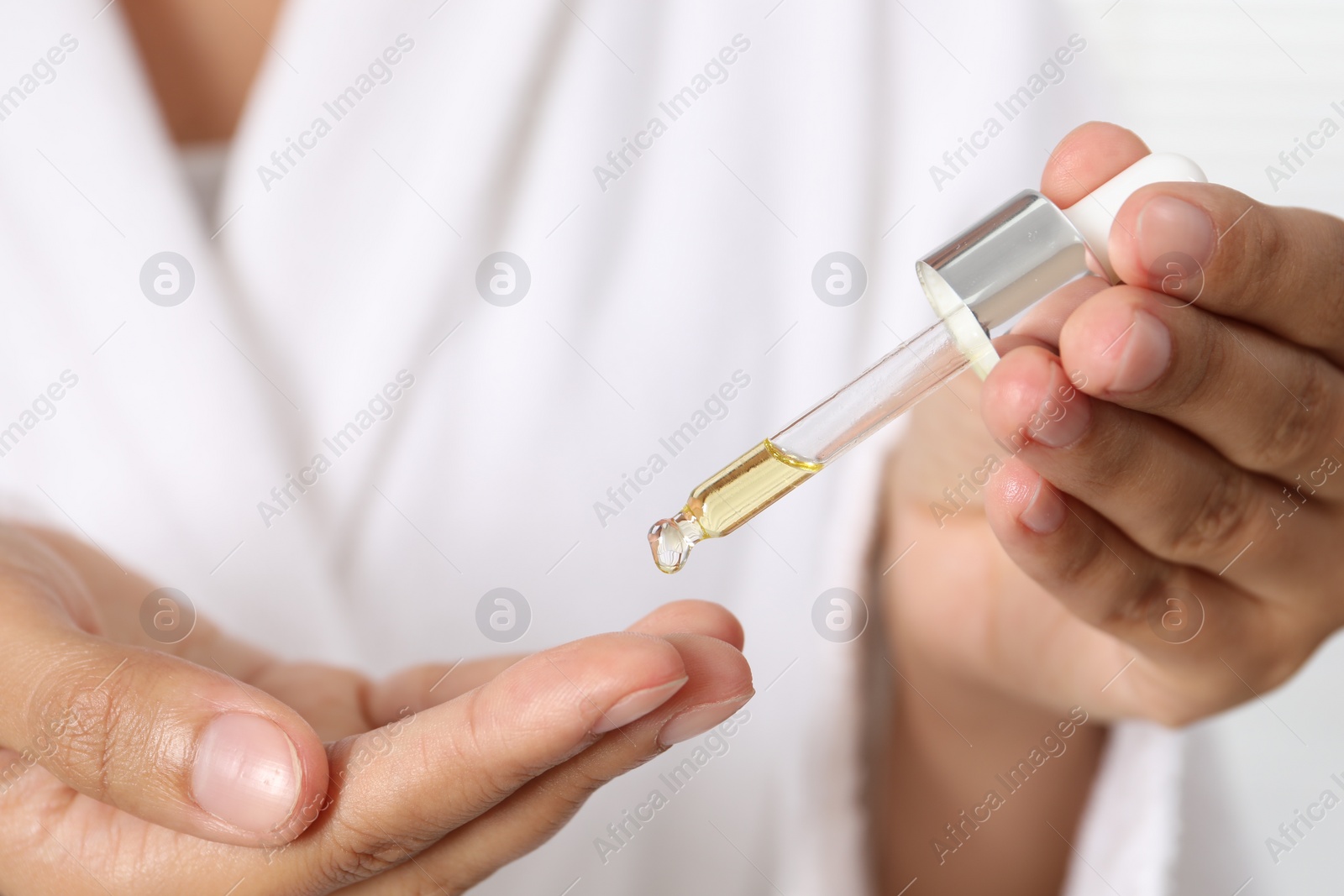 Photo of Woman applying cosmetic serum onto her finger, closeup