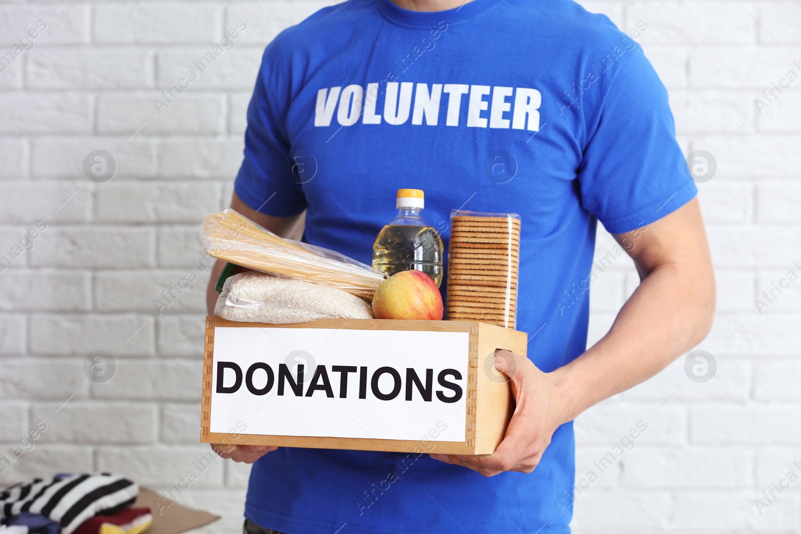 Photo of Male volunteer holding donation box with food products indoors