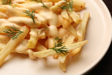 Photo of Delicious french fries with cheese sauce and dill on table, closeup