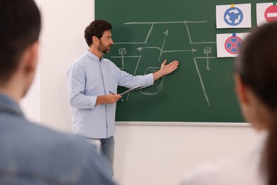 Photo of Teacher explaining traffic rules to audience during lesson in driving school