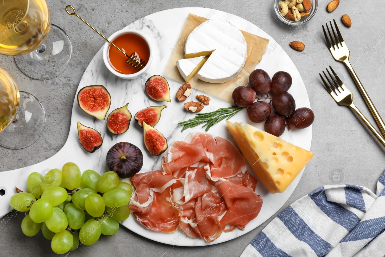 Photo of Delicious ripe figs, prosciutto and cheeses served on grey table, flat lay