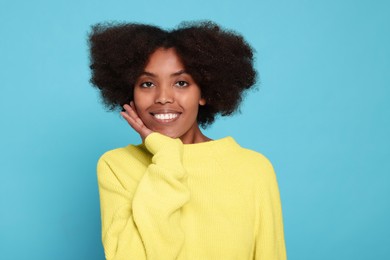 Portrait of smiling African American woman on light blue background