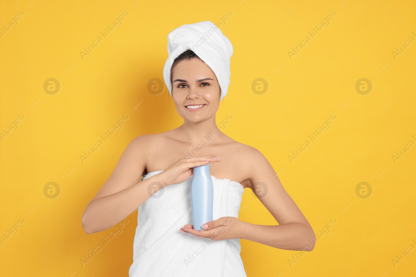 Photo of Beautiful young woman holding bottle of shampoo on orange background