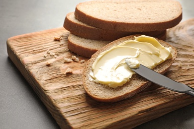 Photo of Spreading butter onto toast with knife on wooden board