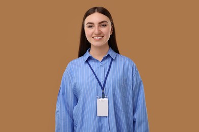 Happy woman with blank badge on brown background