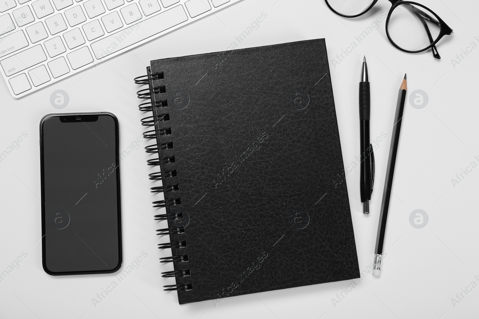 Photo of Flat lay composition with black notebook and smartphone on white table