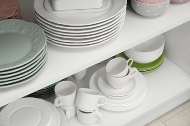 Clean plates, bowls and cups on shelves in cabinet indoors