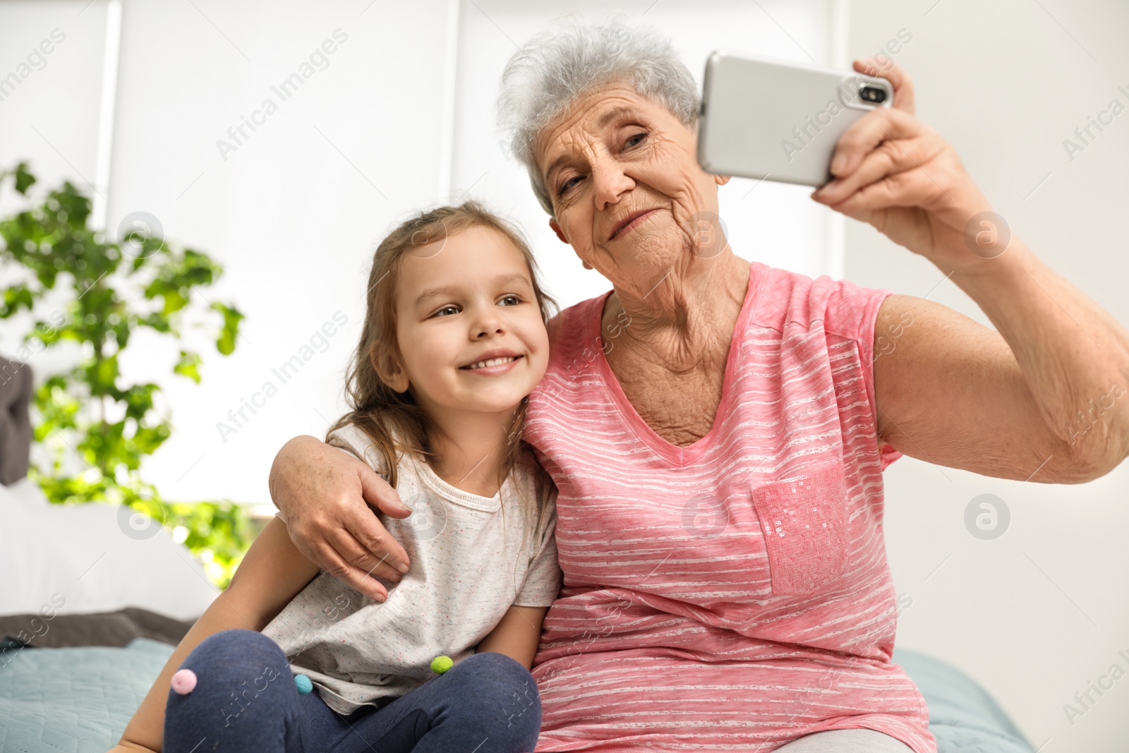 Photo of Cute girl and her grandmother taking selfie  at home