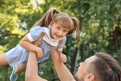 Father having fun with his cute child in green park on sunny day. Happy family