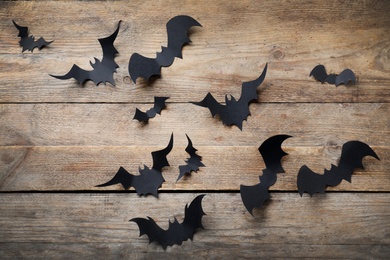 Photo of Paper bats on wooden background, flat lay. Halloween decor