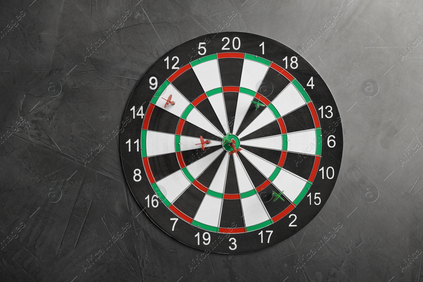 Photo of Dart board with color arrows on grey stone background, top view