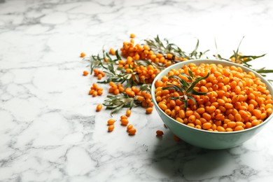 Photo of Ripe sea buckthorn berries on white marble table. Space for text