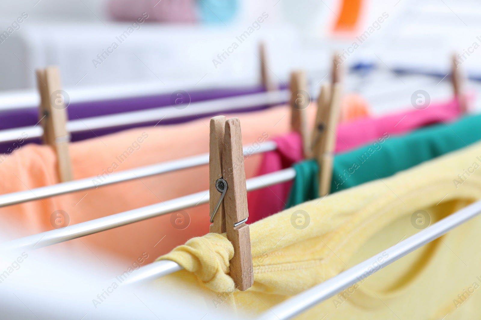 Photo of Clean laundry hanging on drying rack indoors, closeup