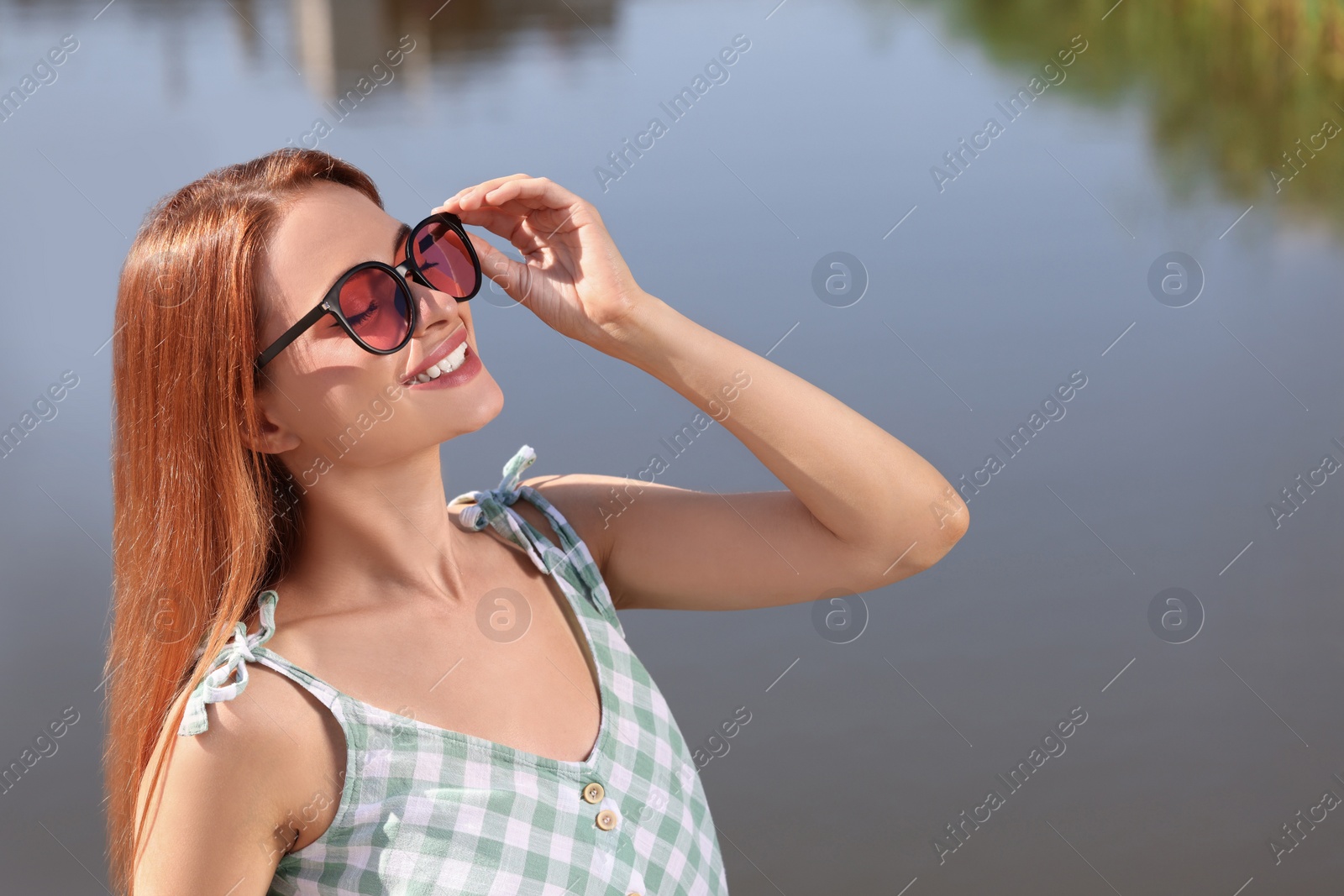 Photo of Beautiful smiling woman in sunglasses near river, space for text