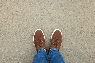 Photo of Man in stylish sneakers standing on asphalt, top view. Space for text