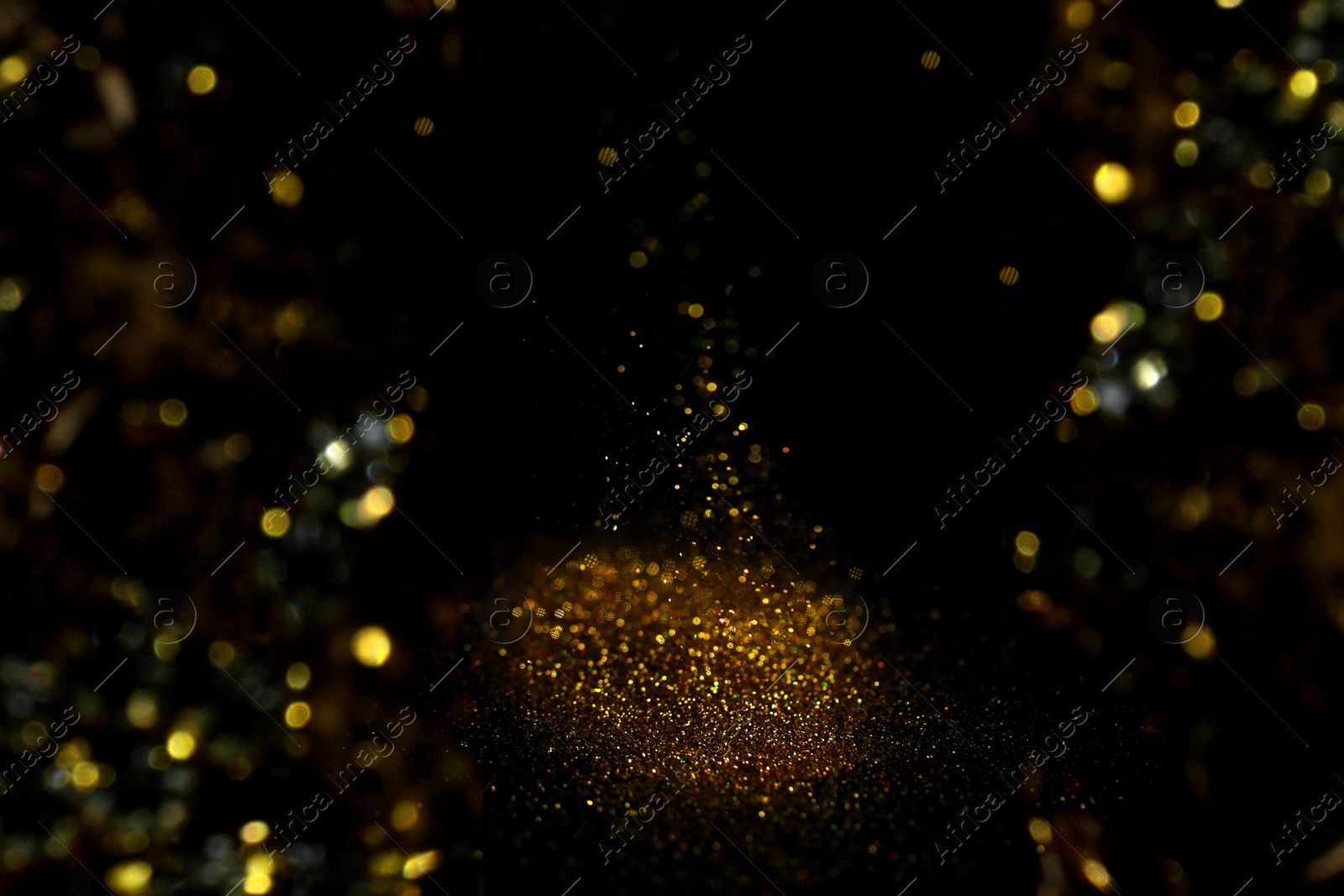 Photo of Sprinkling gold glitter on black background, bokeh effect