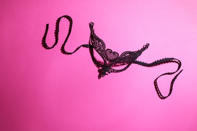 Photo of Black lace mask on pink background, top view with space for text. Sexual role play accessory