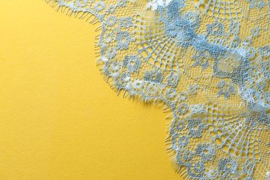 Photo of Light blue lace on yellow background, top view. Space for text