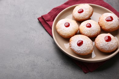 Photo of Hanukkah donuts with jelly and powdered sugar on grey table, space for text