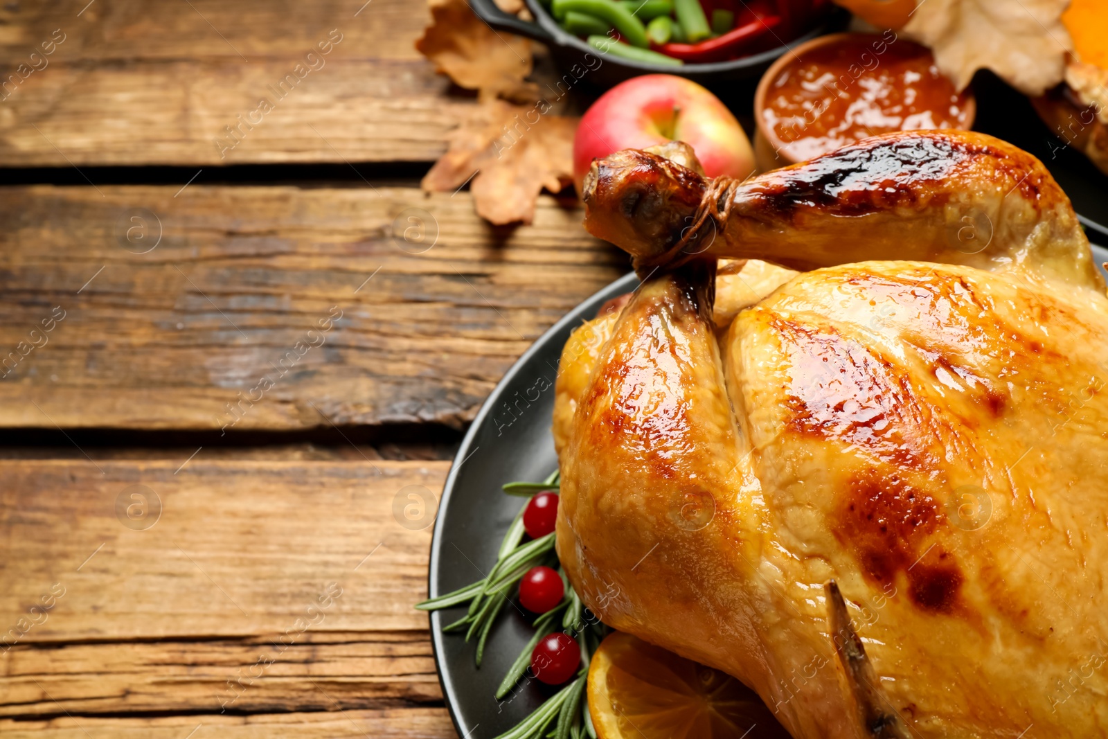 Photo of Traditional Thanksgiving day feast with delicious cooked turkey and other seasonal dishes served on wooden table, closeup. Space for text
