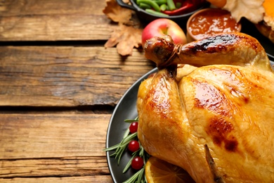 Photo of Traditional Thanksgiving day feast with delicious cooked turkey and other seasonal dishes served on wooden table, closeup. Space for text